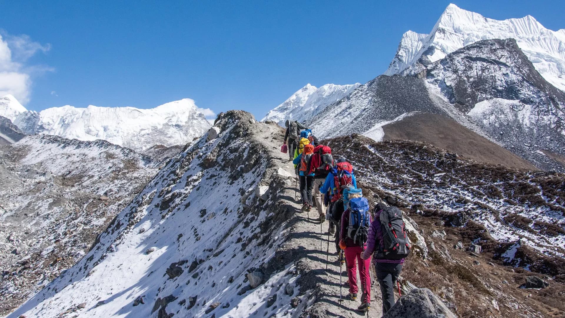 Group of diverse trekkers hiking together on Nepal Himalayan trail with snow-capped peaks, prayer flags, and mountain scenery—perfect for Everest Base Camp adventure tours.